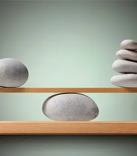 Steine die auf einem Brett im Gleichgewicht balancieren