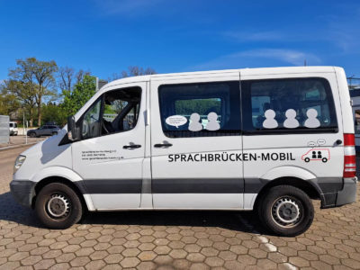 Ein weißer Kleintransporter seitlich steht auf einem großen Platz.
