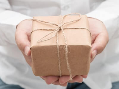 Ein Päckchen wird von zwei Händen vorgehalten